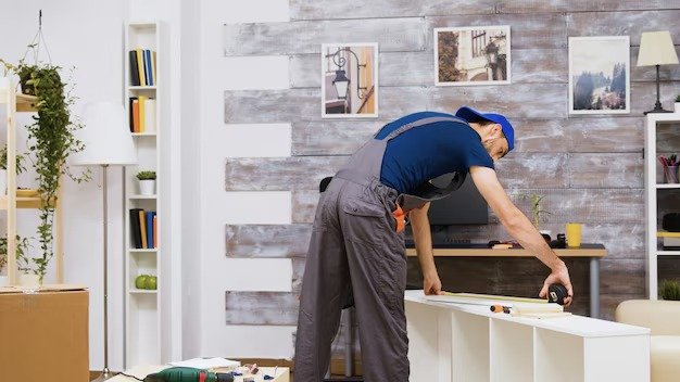 Professional handyman assembling and installing furniture in a residential living room