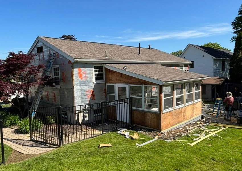 Professional window repair and installation during a residential home renovation with new windows, exterior remodeling, and enclosed sunroom construction.