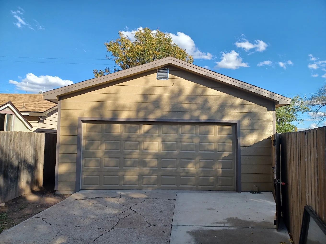 Residential garage exterior with new siding, fresh paint, and overhead garage door